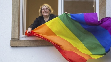 Ann Cathrin Röttger mit Regenbogenflagge am Fenster 