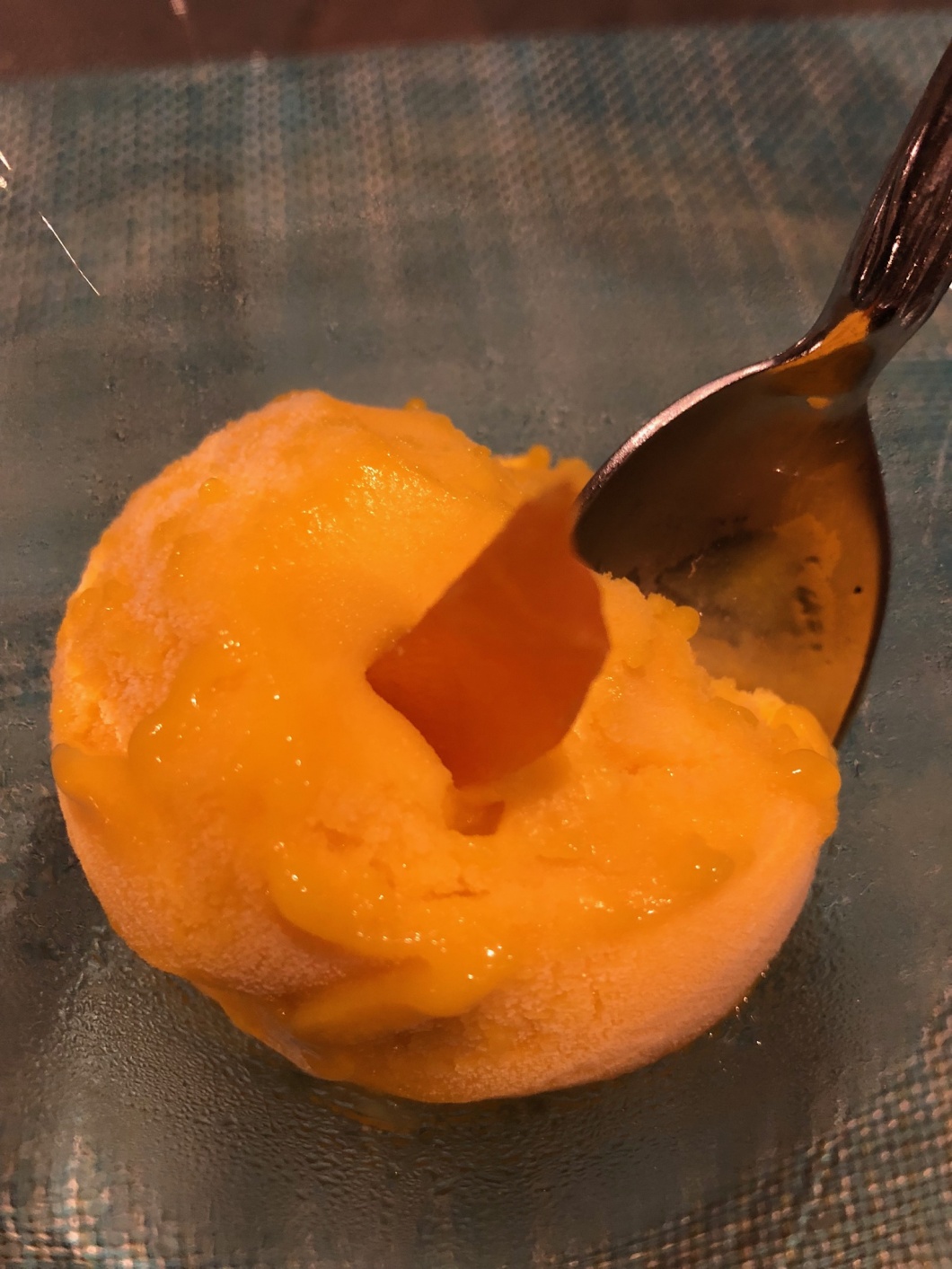 Orangene Eiskugel mit Löffel